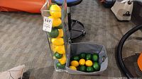 Acrylic vase filled with faux lemons and limes beside fabric basket containing more faux fruit