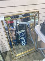 Full view of gold beaded wall mirror leaning against wall