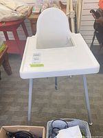 Front view of white high chair showing tray and legs