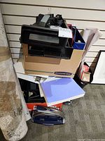 pile of office supplies including binders in a Bankers Box, letter tray, loose papers