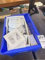 Blue tote containing wall plates, round covers, boxed dimmer, tape rolls