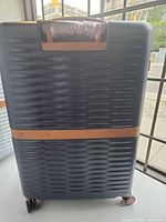 Rear view of navy suitcase showing textured hard shell and lower tan accent band
