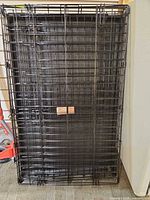Folded black wire dog crate standing upright