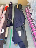 Multiple fabric bolts; center navy and black wool crepe bolts on cardboard cores