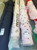 Several fabric bolts; center two are Paoletti pink with poodle print, showing length tags