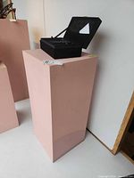 Front and side view of pink pedestal with item tag visible
