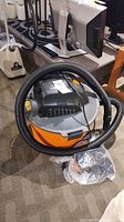 RIDGID wet/dry vacuum with hose coiled on top and accessory bag