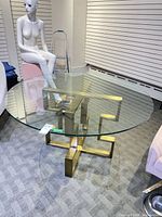 Full view of round glass dining table with brass base