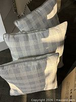 Three light gray plaid throw pillows standing upright