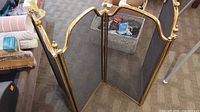 Screen unfolded showing three hinged panels with brass frame and mesh