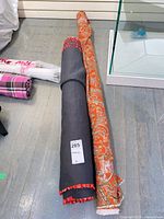Two fabric rolls laid side by side; black textured roll and orange paisley roll visible