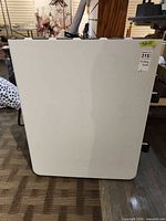 Table folded upright showing white top surface and wheels