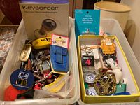 Two bins filled with assorted keychains, packaged Keycorder, hardware pieces visible