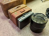 Group shot of three suitcases, one briefcase, one hat box closed