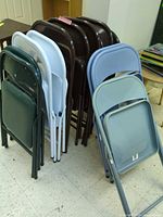 Stack of assorted color folding chairs showing variety and quantity