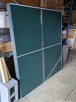 Front view of folded green ping pong table showing playing surface