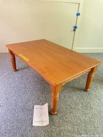 Overall view of light brown lift-top coffee table showing turned legs and flat top
