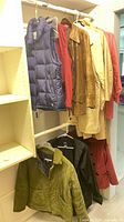 Multiple outerwear items hanging on two closet rods