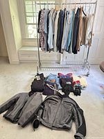Full lot view: clothing rack with tops, items laid on floor