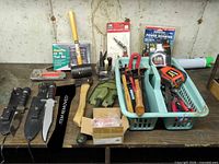 Overall lot on bench showing knives, hatchet, mallet, stapler, tape measure, basket of tools, boxed inverter and tool kit