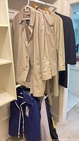 Beige trench coats and navy/grey jackets hanging