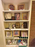 bookshelf displaying framed prints, figurines, crosses, rosaries and booklets