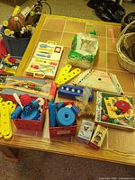 Overview of mixed toys on table—pegboard, medical kit, connector strips, boxed items