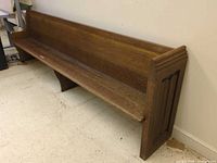 Angled view of full oak pew against wall