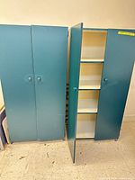 Front view showing both teal cabinets, closed doors, knob pulls