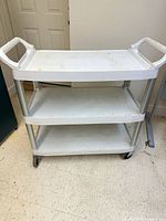 Full view of Rubbermaid 3-tier cart showing shelves, handles, and casters