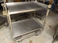 Full view of stainless steel cart showing two shelves and wheel configuration