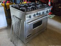 Full view of stainless steel Viking 6-burner range with racks leaning on side