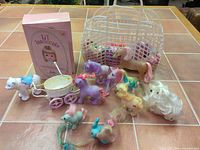 Full lot overview showing boxed doll, carriage, polar bear, basket, multiple ponies and accessories