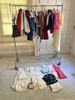Full rack of assorted children’s clothes plus ceremonial items laid on floor