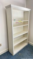 Full view of white bookcase, crown molding top, five shelves