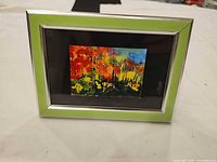 Front view showing green frame, silver trim and abstract watercolor