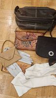 Group shot showing four bags, wallet, two pairs gloves on floor