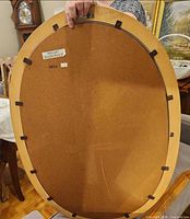 Rear view showing oval shape, backing board, frame material and clips