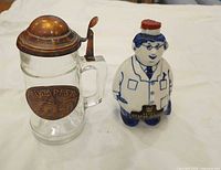 Glass stein with closed lid beside porcelain vodka bottle