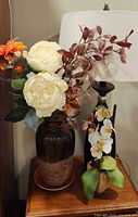 Two potted faux orchid arrangements on tabletop beside lamp
