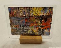 Front view of abstract painting inside clear magnetic frame on wooden stand