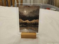 Front view of artwork in acrylic sleeve on wooden stand