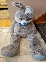 Front view of oversized gray plush animal seated on floor