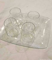 Four tumblers placed on square glass tray
