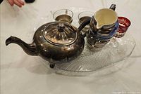 Group showing teapot, creamer, 4 glass cups in holders on glass fish platter