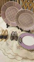 Lot overview showing two lavender plates, cup with saucer, three shoe figurines and two stands