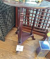 Full view of pedestal side table showing round top, three turned legs, tri-foot base, finish wear
