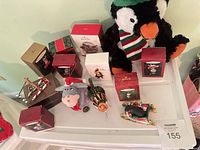 Assorted boxed Hallmark ornaments, plush penguin, plush donkey and loose ornaments displayed together