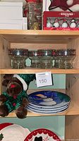 Shelf view showing four glass dessert cups, stacked snowman plates, plush reindeer-elf toy