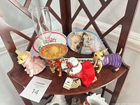Shelf showing three dressed Chihuahua figurines, two oval Chihuahua signs, and a champagne flute
